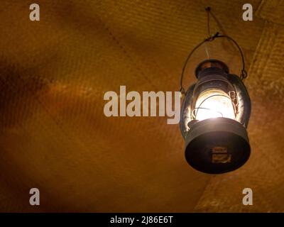 Helles Licht in einer alten Laterne, die in einem alten Raum hing Stockfoto