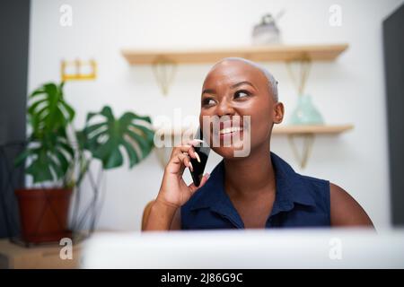 Eine junge schwarze Geschäftsfrau lächelt bei einem Telefonanruf im Büro Stockfoto