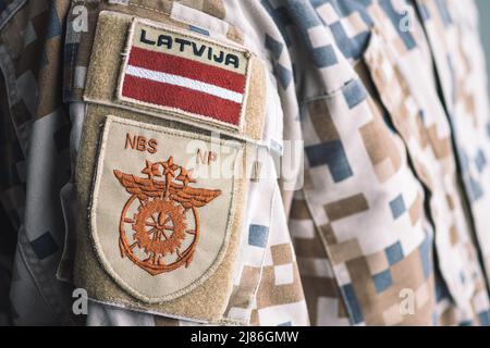 Lettische nationale Streitkräfte mit der Flagge Lettlands und dem Emblem des Unterstützungskommandos auf einer Soldatenuniform, NATO-Einheit zur Integration von Truppen Stockfoto