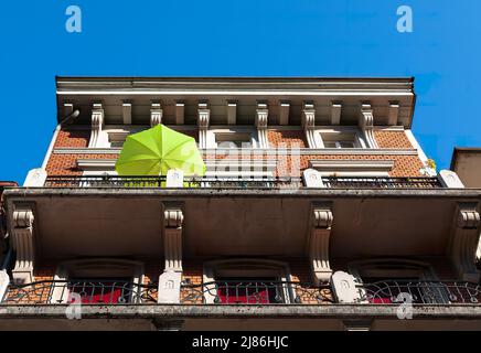Biel, Schweiz - 11. Mai 2022: Blick auf das alte historische Haus in Biel mit einem grünen Sonnenschirm auf dem Balkon Stockfoto