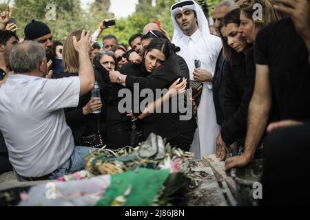 Jerusalem, Israel. 13.. Mai 2022. Palästinensische Trauerbrüder drängen sich um das Grab des getöteten Al Jazeera-Reporters Shireen Abu Akneh auf dem Berg-Zion-Friedhof in der Nähe von Jerusalem. Abu Aklei, 51, eine prominente Persönlichkeit im arabischen Nachrichtendienst des Al-Jazeera-Kanals, wurde am 11. Mai während einer Konfrontation zwischen israelischen Soldaten und Palästinensern in der Stadt Jenin im Westjordanland getötet. Quelle: Ilia Yefimovich/dpa/Alamy Live News Stockfoto