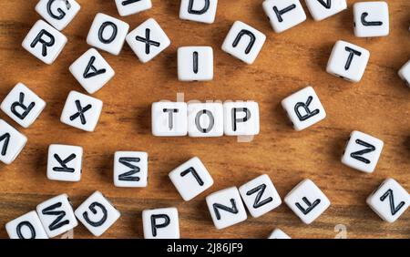 Kleine weiße und schwarze Perlenwürfel auf Holzbrett, Buchstaben in der Mitte buchstabieren OBEN Stockfoto