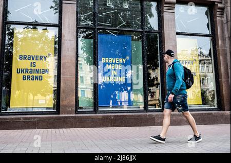 Kiew, Ukraine. 13.. Mai 2022. Mann, der an großen Schildern in den Schaufenstern vorbei geht, auf denen steht: „Bravery is Ukrainian Brand“ und „Bravery made in Ukraine“. (Foto: Michael Brochstein/Sipa USA) Quelle: SIPA USA/Alamy Live News Stockfoto