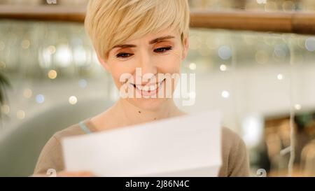 Porträt kaukasischen mittleren Alters Erwachsene 40s Frau lesen Dokument Brief von Freunden Job Benachrichtigung Veranstaltung Einladung gute Nachrichten positive Ergebnisse Stockfoto