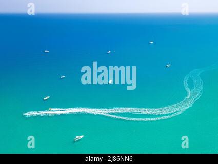 Schnellboot verlässt Spritzweg auf dem Meerwasser. Wassersport am Meer, Luftaufnahme minimal Seeseite Stockfoto