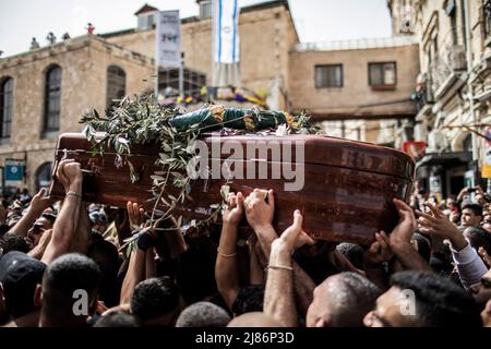 Jerusalem, Israel. 13.. Mai 2022. Palästinensische Trauernde tragen die Schatulle des ermordeten Al Jazeera-Reporters Shireen Abu Akleh während ihrer Trauerprozession zu ihrer letzten Ruhestätte. Abu Aklei, 51, eine prominente Persönlichkeit im arabischen Nachrichtendienst des Al-Jazeera-Kanals, wurde am 11. Mai während einer Konfrontation zwischen israelischen Soldaten und Palästinensern in der Stadt Jenin im Westjordanland getötet. Quelle: Ilia Yefimovich/dpa/Alamy Live News Stockfoto