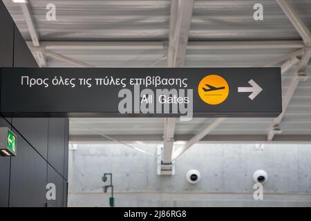 Unterschreiben Sie alle Tore in dieser Richtung auf Griechisch und Englisch am Flughafen Stockfoto