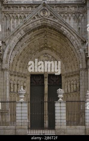 Spanien, Kastilien-La Mancha, Toledo. Kathedrale der Heiligen Maria. Erbaut im gotischen Stil zwischen 1227 und 1493. Hauptfassade. Tor der Vergebung. Erbaut unter der Leitung des Architekten Alvar Martínez (tätig zwischen 1418 und 1440). Es verfügt über einen Bogen mit sechs gotischen Archivoliven, Christus im Pfosten und ein Apostolat in den Pfosten. Im Tympanon befindet sich ein skulpturales Relief, das die Jungfrau darstellt und den heiligen Ildephonsus mit dem Chasuble aufzwingt. Stockfoto