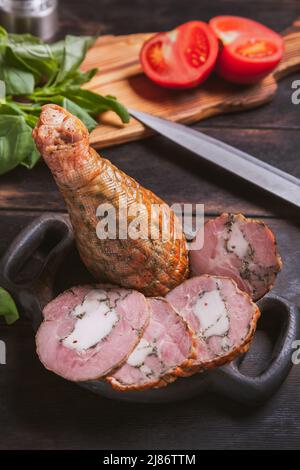 Schneiden aus einem hausgemachten, handgemachten putenfleisch, gekocht und geräuchert mit Zusatz von Hühnerfilet in der Haut eines Hühnerbeins mit Knochen Stockfoto