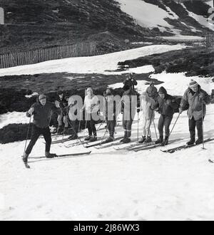 1960s, historisch, Hochland, Schottland, Gruppe von Skifahrern in der Kleidung der Ära, Standing auf den Pisten in einem Skiunterricht mit Lehrer. Stockfoto