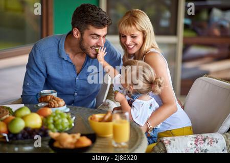 Das Kind ernährt ihren Vater draußen mit Trauben Stockfoto