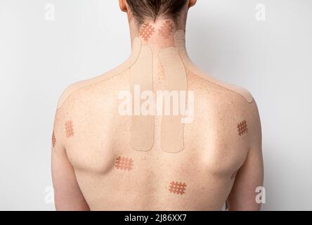 Nahaufnahme des Menschen Rücken und Hals mit verschiedenen Schmerzlinderung Chargen angewendet, Raster Form Schmerzlinderung Chargen und Kinesio-Band. Nackenschmerzen concep. Stockfoto