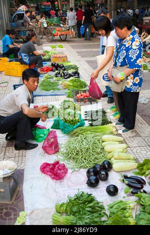 Bürgersteig Marktstand mit Obst und Gemüse auf dem Boden und Kunden auf der Suche nach Produkten zu kaufen. Stadt Xi'an in China VRC. (125) Stockfoto