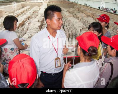 Touristenführer mit einer Gruppe chinesischer Touristen, die die Grube 1 der Terrakotta-Armee im Mausoleum-Museum von Kaiser Qinshihuang in Xi'an, China, besuchen. VRC. (125) Stockfoto