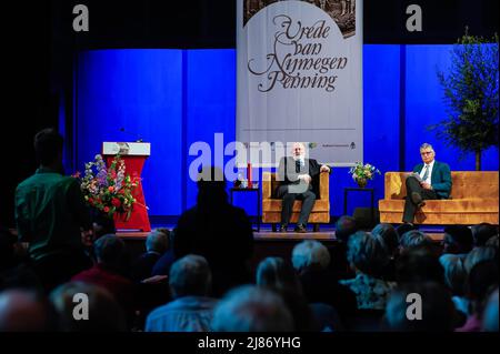 Nijmegen, Niederlande. 12.. Mai 2022. Der Vizepräsident der Europäischen Kommission, Frans Timmermans (L), hört einer Person aus dem Publikum zu. Die "Verträge von Nijmegen-Medaille" ist ein halbjährlicher Preis, der an eine internationale Schlüsselfigur oder eine Organisation verliehen wird, die einen besonderen Beitrag in Politik, Wissenschaft, Wirtschaft oder Kultur zur Entwicklung und Position Europas oder zum europäischen Frieden geleistet hat. In diesem Jahr erhielt Frans Timmermans die Auszeichnung für sein Engagement für Frieden und Zusammenarbeit in Europa. Frans Timmermans ist ein entschiedener Befürworter der Rechtsstaatlichkeit und hat sich jahrelang für den Imp eingesetzt Stockfoto