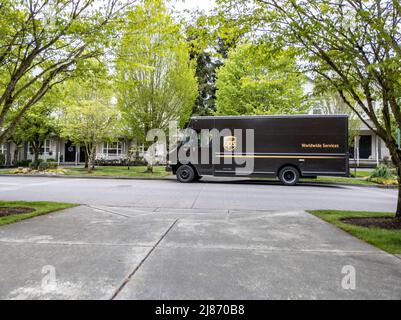 Mill Creek, WA USA - ca. Mai 2022: Vorderansicht eines braunen UPS-Lieferwagens außerhalb eines Wohnhauses, der eine Lieferung vornimmt. Stockfoto