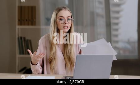 Wütend Geschäftsfrau blonde Mädchen mit Brille im Büro wütend Gespräch Remote Streit Videokonferenz Gespräch mit Kollegen Kollegen Stockfoto