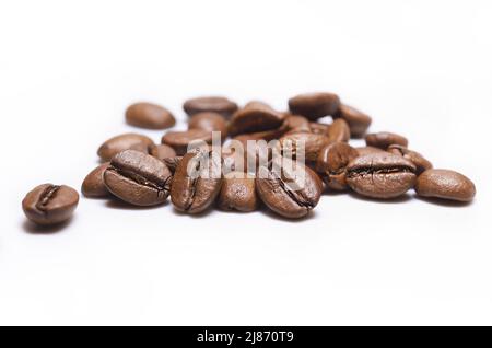 Stapel von Bohnen mit mittelbraöstlichem Kaffee auf weißem Hintergrund. Geröstete Arabica-Kaffeebohnen. Geröstete Kaffeebohnen auf weißem Hintergrund. Koffeinaroma Stockfoto