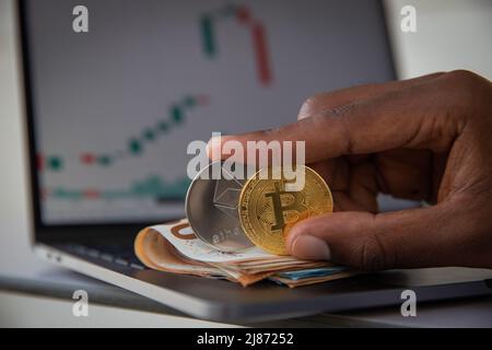 Nahaufnahme von zwei Bitcoin- und Ethereum-Münzen mit Euro-Banknoten und -Charts, Trading Profit Concept Stockfoto