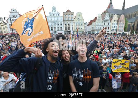 Rostock, Deutschland. 13.. Mai 2022. Fans und Spieler der Rostock Seawolves stehen auf dem Neuen Markt und feiern die Beförderung der Herren-Basketballmannschaft der Rostock Seawolves zur Basketball-Bundesliga 1.. In der letzten Sekunde hatte das Team mit 77:76 in Jena gewonnen und steigt damit erstmals in der Bundesliga. Quelle: Danny Gohlke/dpa/Alamy Live News Stockfoto