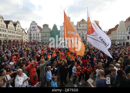 Rostock, Deutschland. 13.. Mai 2022. Fans der Rostock Seawolves stehen auf dem Neuen Markt und feiern die Beförderung der Herren-Basketballmannschaft der Rostock Seawolves zur Basketball-Bundesliga 1.. In der letzten Sekunde hatte das Team mit 77:76 in Jena gewonnen und steigt damit erstmals in der Bundesliga. Quelle: Danny Gohlke/dpa/Alamy Live News Stockfoto