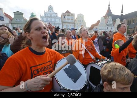 Rostock, Deutschland. 13.. Mai 2022. Fans der Rostock Seawolves stehen auf dem Neuen Markt und feiern die Beförderung der Herren-Basketballmannschaft der Rostock Seawolves zur Basketball-Bundesliga 1.. In der letzten Sekunde hatte das Team mit 77:76 in Jena gewonnen und steigt damit erstmals in der Bundesliga. Quelle: Danny Gohlke/dpa/Alamy Live News Stockfoto