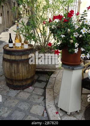 Altes Holzweinfass mit Weinflaschen auf neben Blumentopf in der Straße in den alpen, frankreich Stockfoto