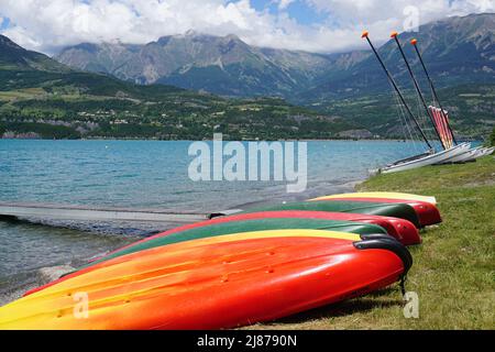 Bunte Kanus Reihen sich am Strand in Serre Ponçon, Südalpen, Frankreich an Stockfoto