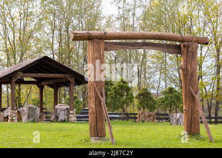 Ein Holzbogen und ein Holzpavillon stehen auf dem Gebiet neben dem Anwesen. Stockfoto