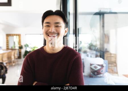 Ein selbstbewusster junger asiatischer Mann, der zu Hause lächelt Stockfoto