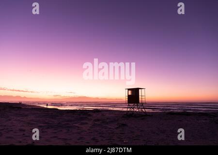 Blick auf Silhouette Rettungsschwimmer Hütte am Sandstrand gegen Meer und klaren lila Himmel, Kopierraum Stockfoto