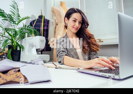 Junge kreative Brünette Frau in einem gemütlichen Studio, Start von kleinen Schneiderei Geschäft Stockfoto