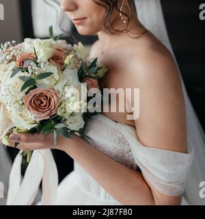 Die Braut hält einen Blumenstrauß in der Nähe ihres Gesichts. Nahaufnahme. Hochwertige Fotos Stockfoto