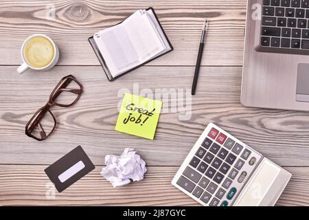 Flache Büroarbeiten Zubehör und tolle Arbeit auf Haftnotiz geschrieben. Taschenrechner mit Laptop-Brille und Tasse Kaffee. Stockfoto