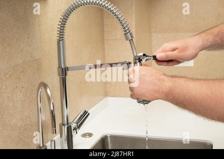 Reparieren eines Wasserhahns in der Küche mit einem Schraubenschlüssel. Klempner Stockfoto