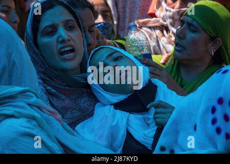 Srinagar, Indien. 12.. Mai 2022. Verwandte trauern, während Menschen in seinem Heimatdorf Gudoora Pulwama einen Sarg mit dem Leichnam des ermordeten Polizeidiensthabers Reyaz Ahmad Thokar tragen. Es wird vermutet, dass Thokar von Militanten außerhalb seines Wohnsitzes in Süd-Kaschmir getötet wurde. (Foto von Faisal Bashir/SOPA Images/Sipa USA) Quelle: SIPA USA/Alamy Live News Stockfoto
