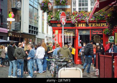DUBLIN, IRLAND - MAI 2018: Geschäftiges Alltagsleben von Touristen und Stadtbewohnern in Dublin, Irland. Menschen, die an einem sonnigen Tag am berühmten Temple Bar Pub vorbei laufen. Stockfoto