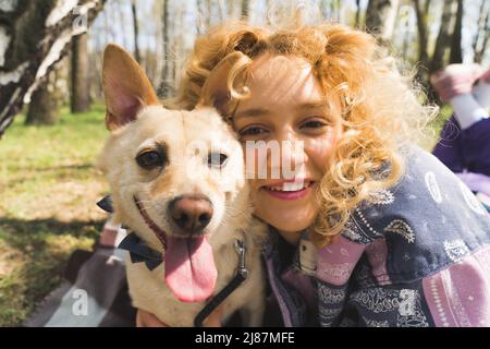 Selfie eines jungen blonden Mädchens und ihres Hundes im Park Medium Nahaufnahme im Freien Menschen-Tiere Freundschaft. Hochwertige Fotos Stockfoto