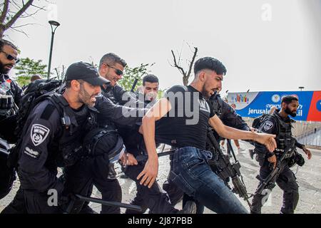 Jerusalem, Israel. 13.. Mai 2022. Israelische Polizeibeamte drücken und treten einen palästinensischen Jugendlichen während der Trauerprozession von Abu Aklei. Abu Aklei wurde am Mittwochmorgen im besetzten Westjordanland getötet, als sie einen israelischen Angriff auf die Stadt Jenin verdeckte. Zeugen sagten, dass sie von einem israelischen Soldaten getötet wurde. Die israelische Armee sagte am Freitag, dass Frau Abu Aklei, obwohl es möglich war, versehentlich durch einen israelischen Brand getötet wurde; ihre ersten Ermittlungen lassen vermuten, dass sie auch von einem palästinensischen Schützen getroffen worden sein könnte. (Foto von Eyal Warshavsky/SOPA Images/Sipa USA) Quelle: SIPA USA/Alamy Live News Stockfoto