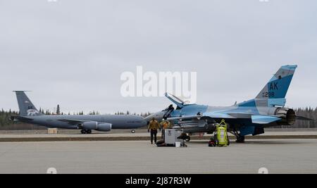 Ein US Air Force KC-135 Stratotanker, der dem 168. 1 Air Betanking Wing zugewiesen wurde, hebt von der Start- und Landebahn ab, während die der 18. Airmen Maintenance Unit zugewiesenen Airmen während DES FLUGES am 10. Mai 22 2022 unter DER ROTEN FLAGGE Alaskas (Alaska) einen Vorflugbetrieb auf der Eielson Air Force Base, Alaska, durchführen. Diese Übung bestärkt das fortgesetzte Engagement der USA für die Region als pazifischer Staat, Führer und Macht. (USA Luftwaffe Foto von Senior Airman Jose Miguel T. Tamondong) Stockfoto