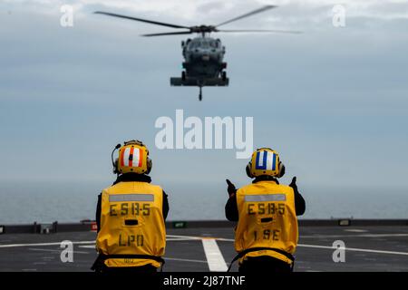 Sea of Japan (12. Mai 2022) – Mate Marcelo Sunga von Chief Aviation Boatswain und Mate Airman Levontae Fleming von Aviation Boatswain, der der USS Miguel Keith (ESB 5) zugewiesen wurde, führen einen an das Sea Combat Squadron (HSC) 25 des Hubschraubers MH-60s Sea Hawk befestigten Hubschrauber, Ablösung 6 während der Landung auf dem Deck von Noble Vanguard. Noble Vanguard dient als Befähigung zur Verstärkung der Taktik und Techniken verschiedener Missionsgruppen, die zur regionalen Stabilität beitragen. (USA Navy Foto von Mass Communication Specialist 2. Class Gregory A. Pickett II/VERÖFFENTLICHT) Stockfoto