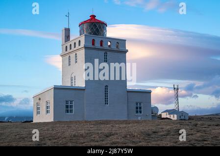 Der berühmte Leuchtturm auf der Halbinsel Dyrhólaey, Dyrhólaeyjarviti auf Isländisch, gegen einen blauen Himmel mit dramatischen Wolken, Island, in der Nähe von Vík í Mýrdal Stockfoto