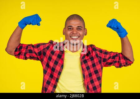 lateinamerikanischer brasilianischer Reinigungsmann mit Ribon-Handschuhen auf gelbem Hintergrund Stockfoto