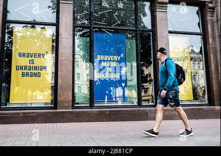 Kiew, Ukraine. 13.. Mai 2022. Der Mensch geht an großen Schildern in den Schaufenstern vorbei, auf denen steht: „Die Marke der Ukraine ist tagend“ und „die Marke der Ukraine ist tagend“. Kredit: SOPA Images Limited/Alamy Live Nachrichten Stockfoto