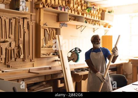 afroamerikanischer reifer Zimmermann, der Holz in der Werkstatt untersucht Stockfoto