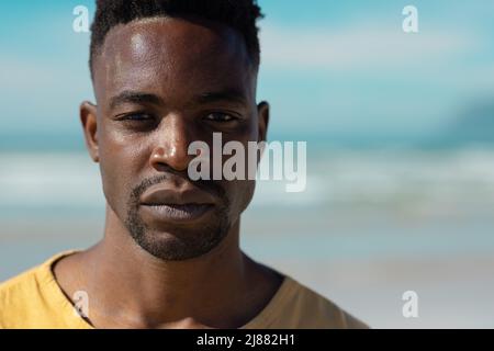 Nahaufnahme eines gutaussehenden, seriös selbstbewussten jungen afroamerikanischen Mannes am Strand an einem sonnigen Tag Stockfoto