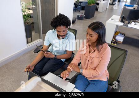 Aus der Perspektive von Kollegen aus der Vogelwelt, die am Laptop diskutieren, während sie am modernen Arbeitsplatz sitzen Stockfoto
