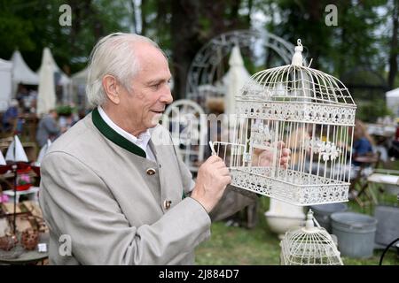 Dobbelin, Deutschland. 13.. Mai 2022. 13. Mai 2022, Sachsen-Anhalt, Döbbelin: Alexander von Bismarck schaut auf der Messe auf einen Vogelkäfig.zum achten Mal findet auf 8 Hektar "LebensArt", der Messe für Garten, Wohnen und Lifestyle auf Schloss Bismarck Döbbelin, statt. Weit über 120 Aussteller präsentieren sich bis Sonntag im Schlossgarten, alles rund um das Thema Garten, Dekorationen und Blumen. Foto: Peter Gercke/dpa Quelle: dpa picture Alliance/Alamy Live News Stockfoto