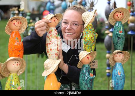 Dobbelin, Deutschland. 13.. Mai 2022. 13. Mai 2022, Sachsen-Anhalt, Döbbelin: Aussteller Janine Bockus aus Bamberg, richtet ihre Keramikgärtner aus. Zum achten Mal findet auf 8 Hektar 'LebensArt', der Messe für Garten, Wohnen und Lifestyle auf Schloss Bismarck Döbbelin, statt. Weit über 120 Aussteller präsentieren sich bis Sonntag im Schlossgarten, alles rund um das Thema Garten, Dekorationen und Blumen. Foto: Peter Gercke/dpa Quelle: dpa picture Alliance/Alamy Live News Stockfoto