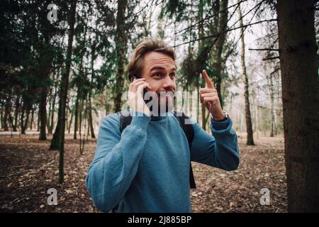 Junge erwachsene Mann am Telefon zu sprechen stehend über weiße Mauer mit Hand betonte am Kopf, mit Scham und Überraschung Gesicht schockiert, wütend und frustr Stockfoto